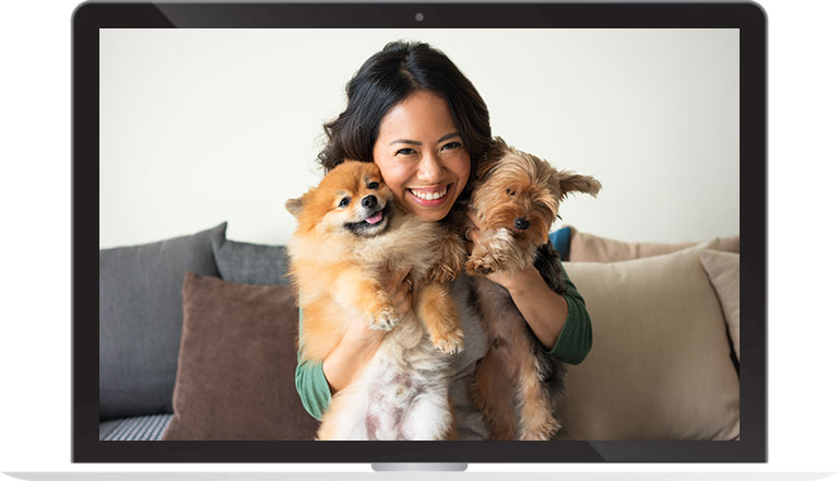 woman hugging two small dogs while smiling