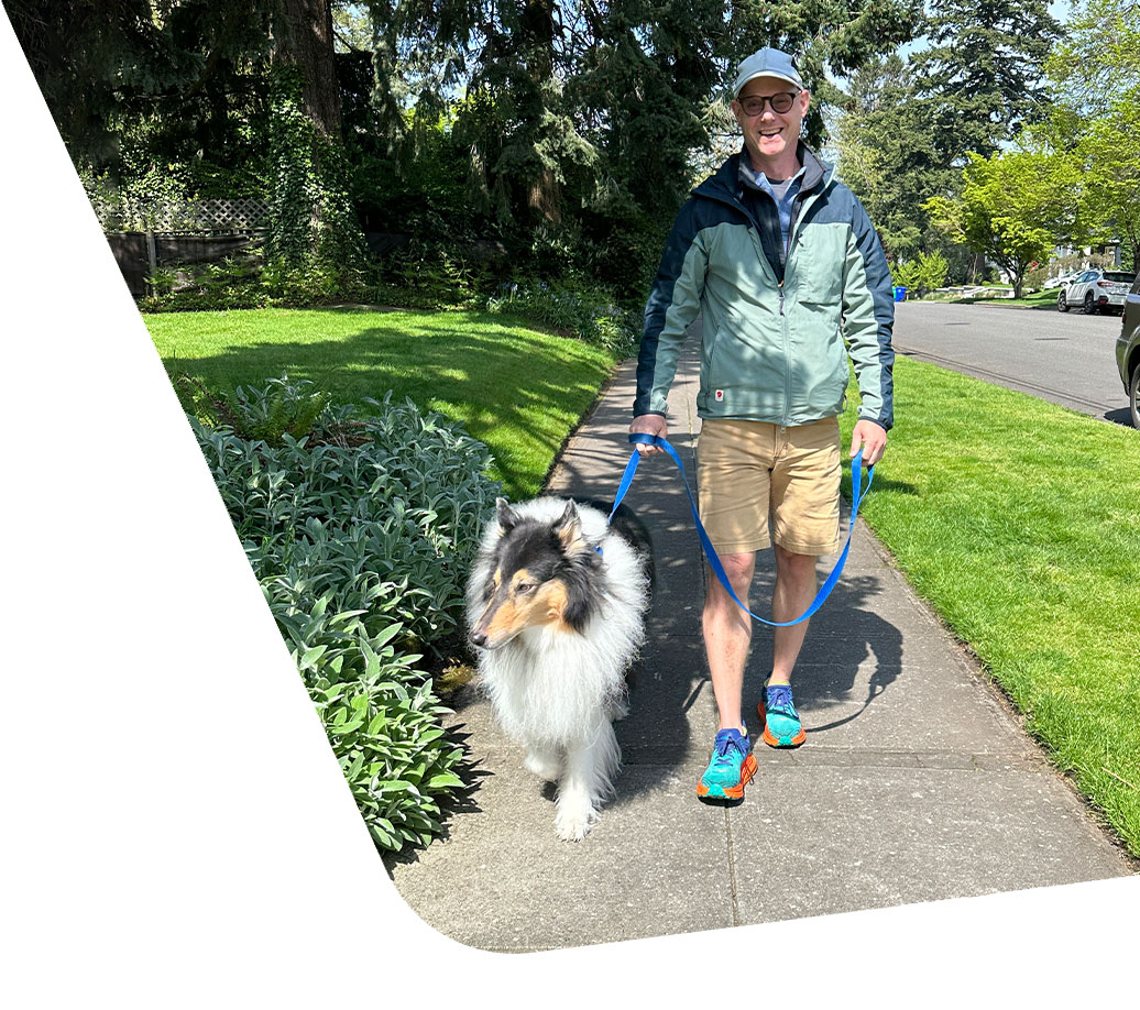 Doug Duncan with a dog on a leash during a walk down a side path.
